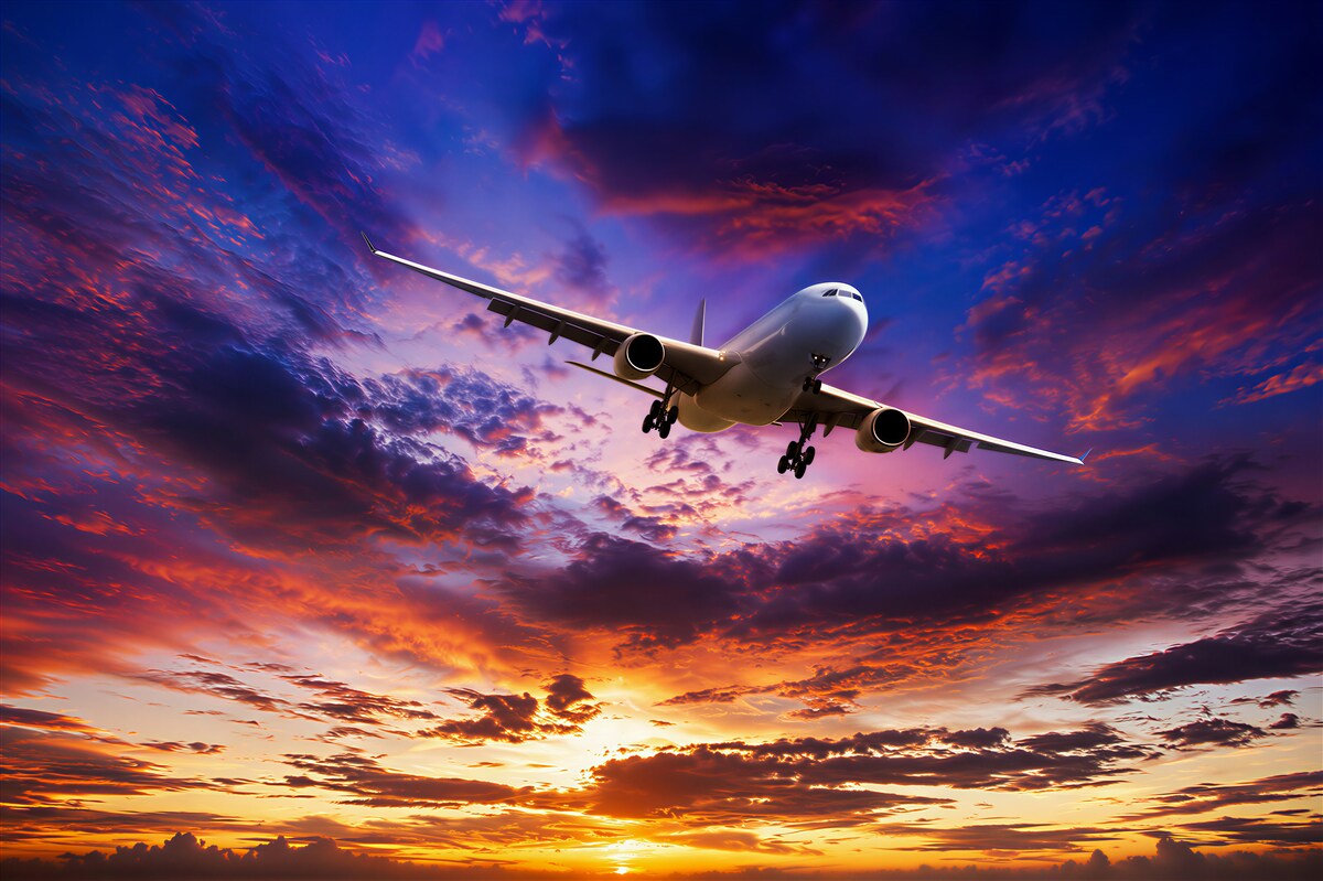 Papier peint avion volant devant un ciel de coucher de soleil